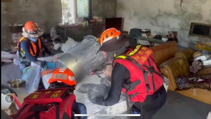 消防局隊員在積水中深入民宅，找尋還有可能生還的跡象